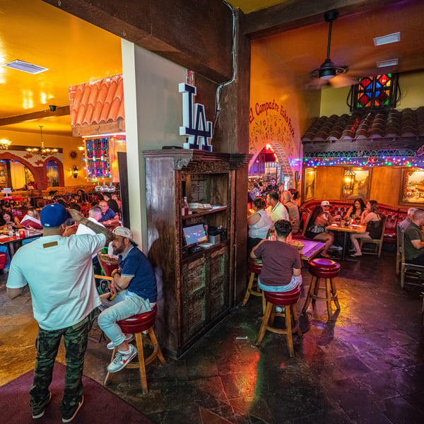 Bustling El Compadre Echo Park restaurant interior with patrons, colorful lights, and traditional Mexican decor.