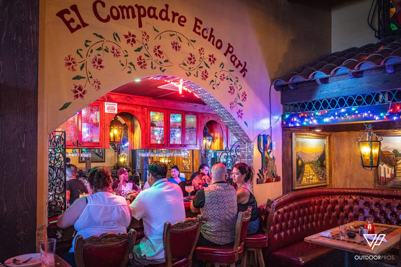 Lively bar scene at El Compadre Echo Park with patrons, colorful lights, and traditional decor.