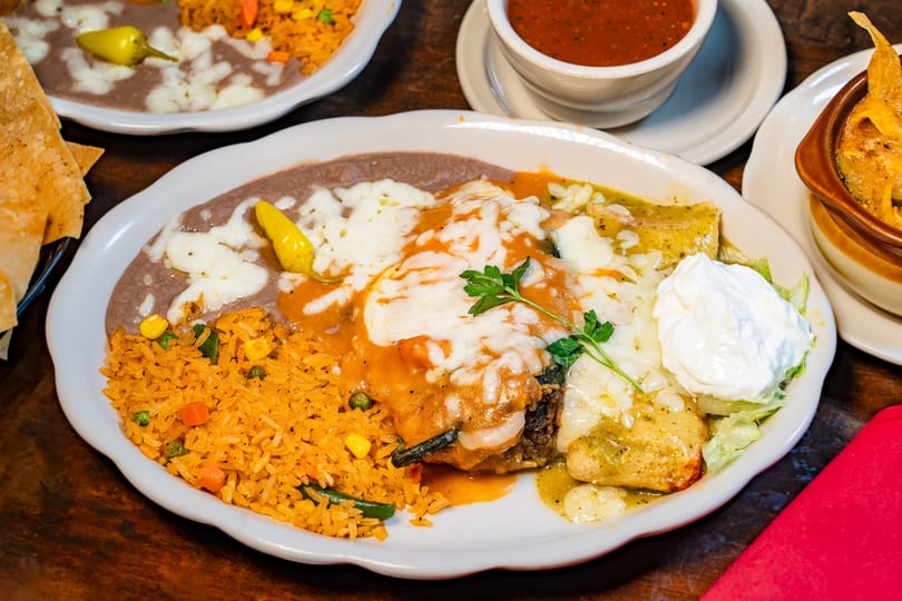 Mexican combo plate with chile relleno, enchiladas, rice, beans, and sour cream.