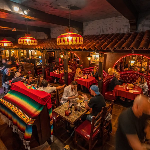 Busy restaurant interior with many people dining in a warm, dimly lit, Mexican-themed setting.